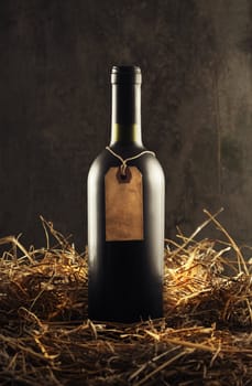 Bottle of red wine in the straw, copy space on vintage label