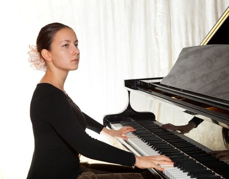 Young beautiful girl playing the piano with a raised lid