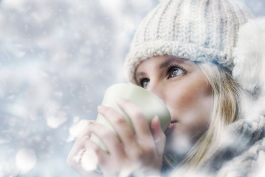 Young woman wearing winter clothes having a hot drink 