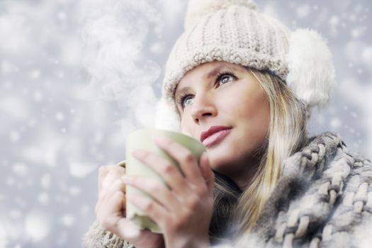 Young woman wearing winter clothes having a hot drink 