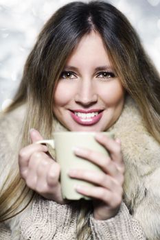 Young woman wearing winter clothes having a hot drink 