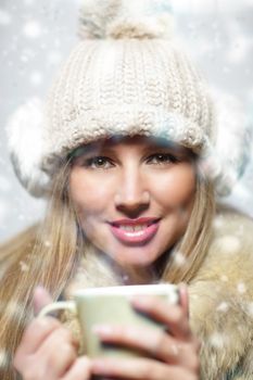 Young woman wearing winter clothes having a hot drink 