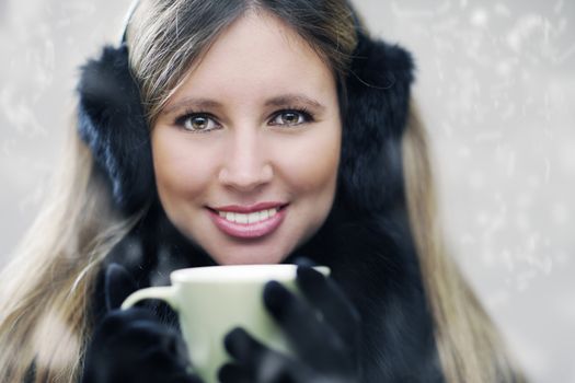 Young woman wearing winter clothes having a hot drink 