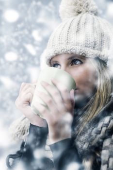 Young woman wearing winter clothes having a hot drink 