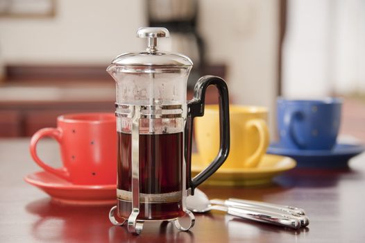 Freshly brewed black coffee with three colorful cups.