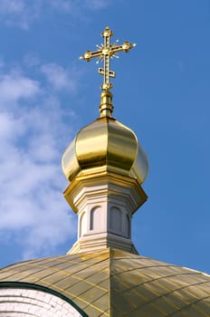 Close-up of Golden crucifix and Cupola of Orthodox church and blue sky with clouds