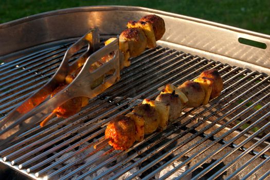 Cooking a few Meat Brochettes on a Barbecue outside in the garden