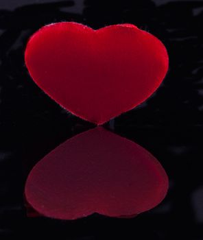 Tissue red heart reflecting over black surface