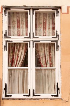 Very old wooden window with flowers on curtains