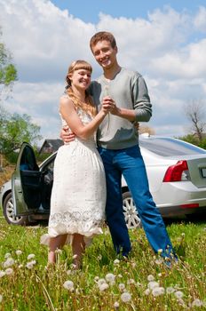 Happy beautiful young couple standing near the car
