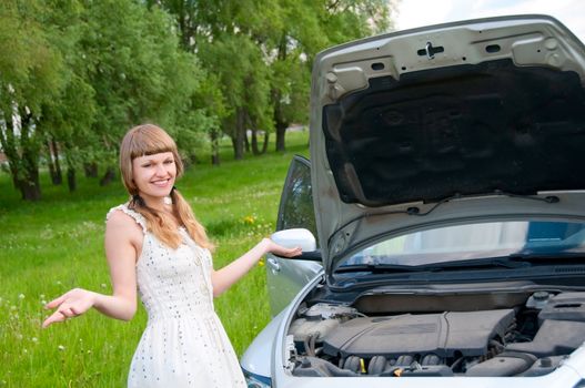 Worried young woman near her broken car with non-urban background