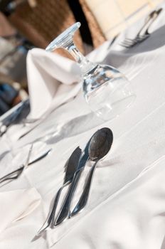 Dining tables ready for customers, outdoor evening. Shallow depth of fields, focus on the spoon top.