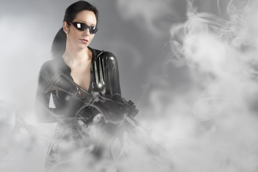 Sexy woman holding gun with helmet over smoke