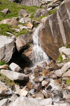 Waterfall on a mountain slope covered. Focus on the waterfall