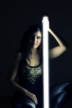 View of a beautiful girl in dark leather clothes holding a light tube.