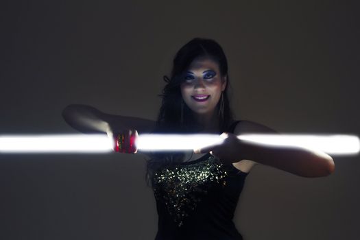 View of a beautiful girl in dark leather clothes holding a light tube.