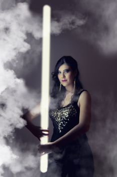 View of a beautiful girl in dark leather clothes holding a light tube.