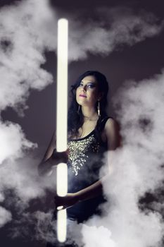 View of a beautiful girl in dark leather clothes holding a light tube.