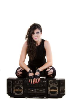 View of a beautiful girl in dark leather clothes against a white background holding a large retro radio.