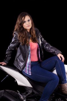 View of a beautiful young girl next to a white motorbike in a studio environment. 