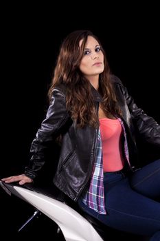 View of a beautiful young girl next to a white motorbike in a studio environment. 