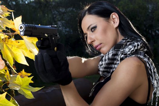 View of a beautiful action girl holding a weapon in a outdoor location.