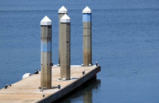A dock in a harbor for sailboats with poles.