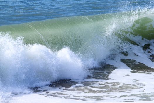 Closeup of a wave breaking near the beach.