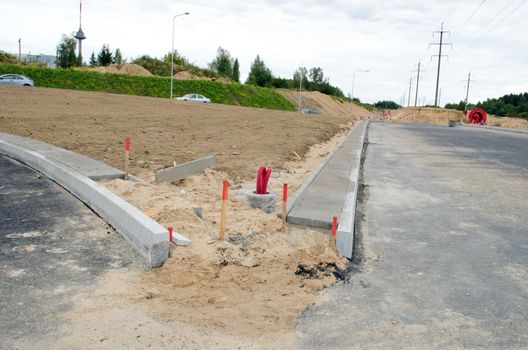 building new road construction site cars going roundabout and lighting pole wires lay.