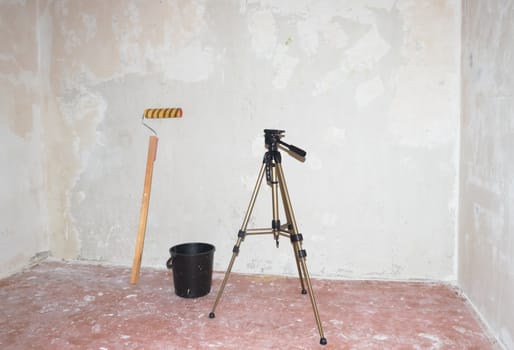 Roller for  putty, bucket and a tripod against the background of putty walls