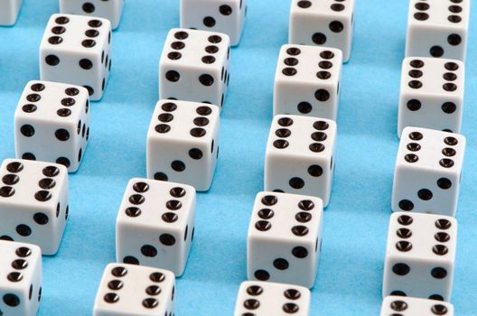 closeup of white gamble dice with six black dots on blue background.