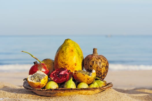 Exotic tropical fruit on the leaves plate, on the sandy beach