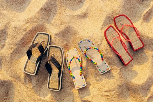 Three pair of beach sandals on the sandy beach