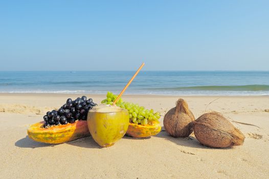Papaya, coconut, nut and grapes on the sandy beach