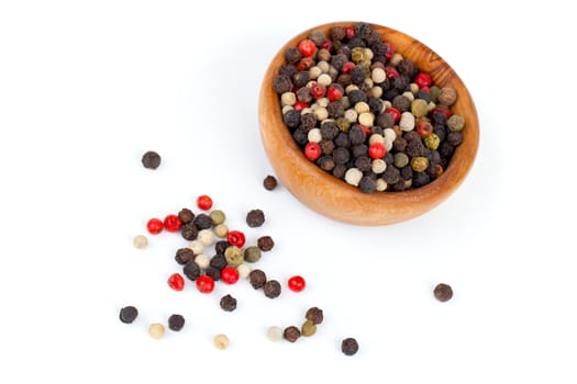 Coloured pepper on a wooden bowl, isolated on white