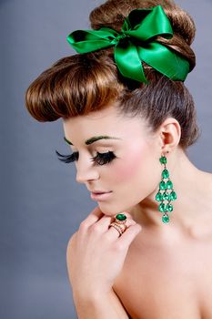 brunette woman with green jewelery and accssesoires on grey background