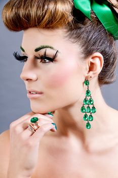 brunette woman with green jewelery and accssesoires on grey background