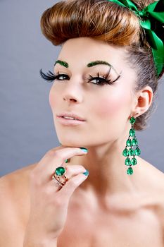 brunette woman with green jewelery and accssesoires on grey background