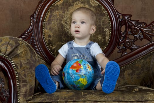 Child with a globe sitting on a chair