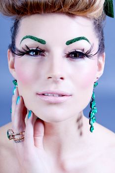 brunette woman with green jewelery and accssesoires on grey background