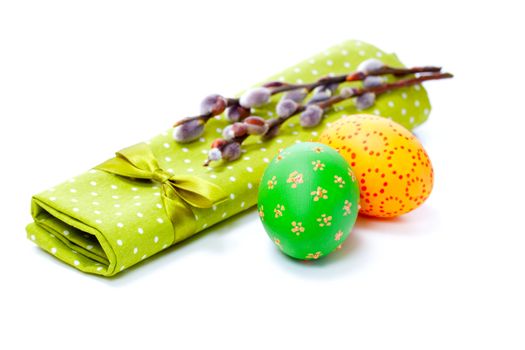 two painted easter eggs with pussy-willow on green serviette, isolated on white background.