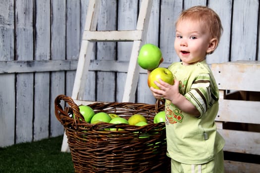 child is around the basket with apples