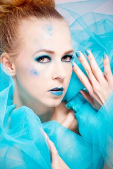 beautiful woman with extreme colorfull make up in turquoise portrait