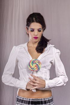 View of a beautiful girl with a colorful lollipop. 