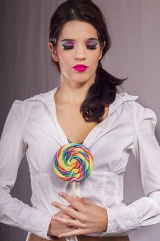 View of a beautiful girl with a colorful lollipop. 