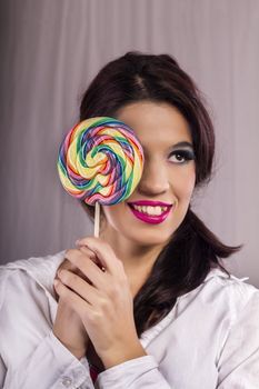 View of a beautiful girl with a colorful lollipop. 