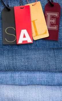 Paper Tags With Sale Sign on Stack of Blue Jeans