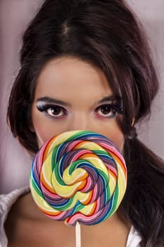 View of a beautiful girl with a colorful lollipop. 