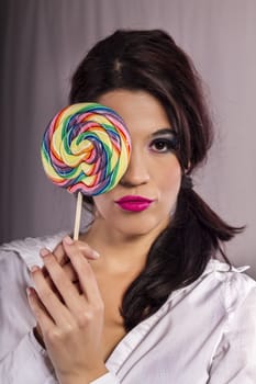 View of a beautiful girl with a colorful lollipop. 