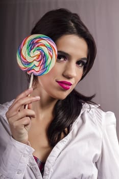 View of a beautiful girl with a colorful lollipop. 